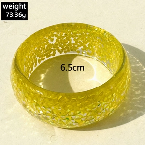 Macro detail of translucent yellow resin bangle with glitter and 6.5cm diameter measurement