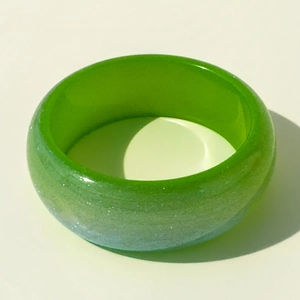 Détail d'un large bracelet en résine vert émeraude avec finition pailletée