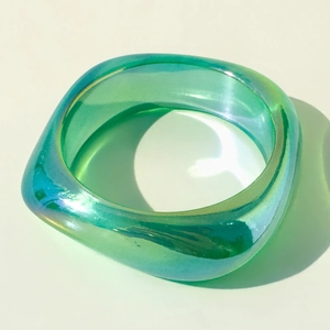 Macro view of a turquoise translucent resin bangle with iridescent holographic finish
