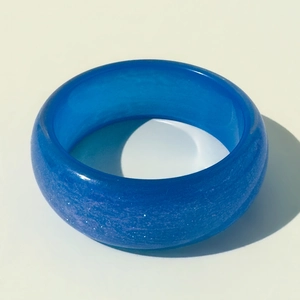 Détail d'un large bracelet en résine bleu saphir avec finition scintillante au laser