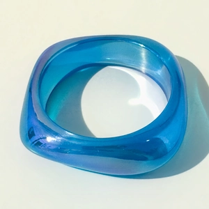 Macro shot of wide square resin bangle with iridescent aurora finish in bright royal blue