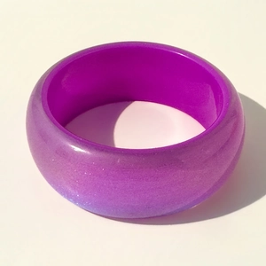 Gros plan sur un large bracelet en résine violette avec paillettes laser et effet nacré