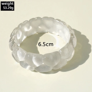 Macro detail of heart-patterned translucent resin bangle with weight and size specs