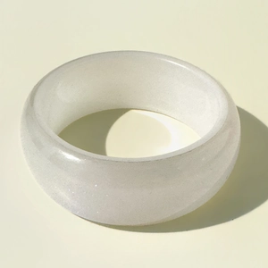 Détail d'une large bague en résine blanche scintillante avec surface polie et texture perlée