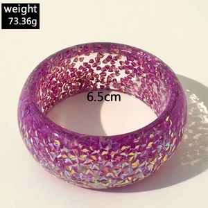 Macro detail of a purple resin chunky bangle featuring colorful glitter and dimensions