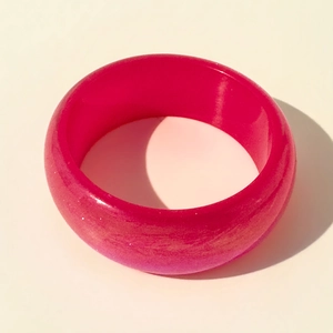 Détail d'un bracelet en résine rouge rose minimaliste avec une finition perlée lisse