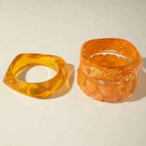 Set of four orange resin bangles featuring glitter inserts and embossed heart patterns