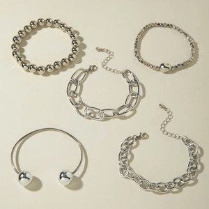 Macro shot of a five-piece silver chain bracelet set with heart charm and lobster clasp
