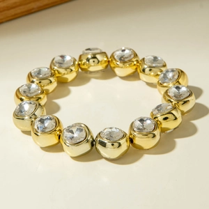 Close-up of golden beaded bracelet with large faceted clear crystals in square settings