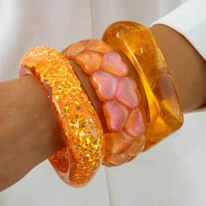 Three-piece set of orange resin chunky bangles featuring amber texture and glittery details