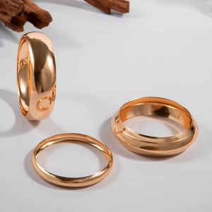 Detailed view of three polished gold rings in wide and thin geometric stackable styles
