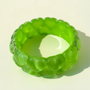 Gros plan d'un bracelet en résine vert vif avec texture bulles et fini translucide