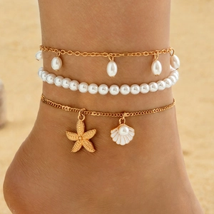 Tobillera bohemia de varias capas en oro con perlas, estrella de mar y concha en la playa
