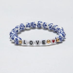 Detail of beaded bracelet with floral ceramic beads, LOVE letters and a red heart charm