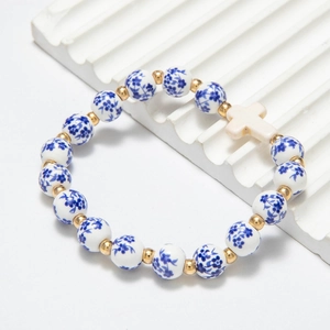 Detail of blue and white floral porcelain beads with a cross charm and gold accents