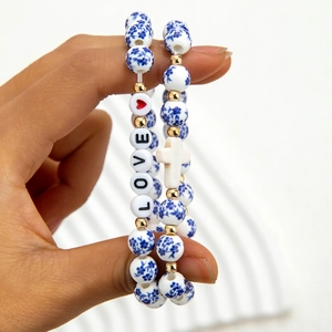 Detail of beaded bracelets with LOVE letters, cross charm and blue floral ceramic beads