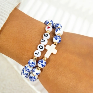 Detail of blue and white ceramic bead bracelets with LOVE letters and white cross pendant