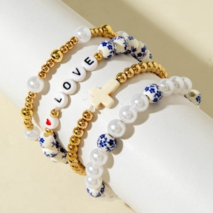 Detail of four-piece beaded bracelet set featuring blue floral ceramic and cross charm