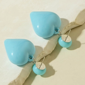 Detailed view of glossy bright blue acrylic heart earrings on a natural stone base
