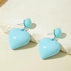 Detail shot of light blue heart-shaped resin earrings on a natural stone surface