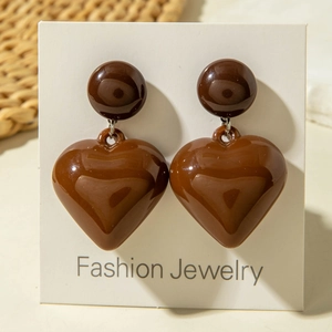 Brown heart-shaped acrylic drop earrings with glossy finish on a white jewelry card