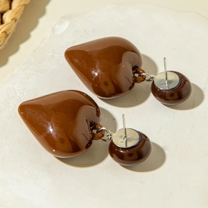 Detailed close-up of dark brown heart-shaped stud earrings on a white stone background