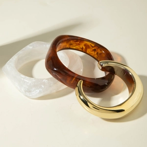 Three-piece bangle set featuring marble resin, tortoiseshell resin, and polished gold metal