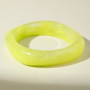 Détail d'un bracelet en résine vert fluo avec textures marbrées et design géométrique