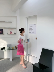 Detalle de un bolso tote de paja trenzada rosa brillante en un entorno de estilo minimalista