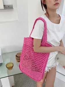Detalle del bolso de hombro de paja de ganchillo rosa vibrante con diseño de malla hueca y asas