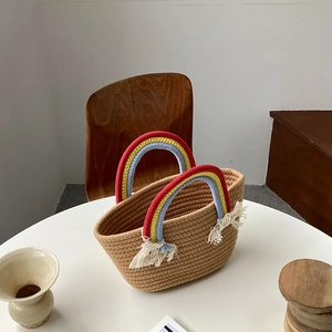 Detalle de bolso de paja tejido con asas de arcoíris y borlas colgantes de color blanco