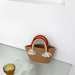 Detalle de bolso tote de paja tejida con asas de arcoíris y borlas de algodón blanco