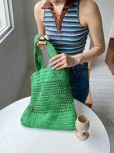 Detalle del bolso tote de ganchillo verde con diseño calado y asas largas de hombro