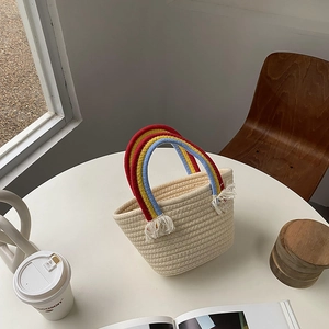 Detalle del bolso tejido con asa de arco iris y detalles de borlas blancas suaves