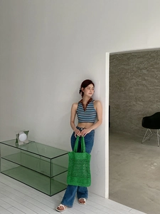 Detalle de un bolso tote de paja tejida verde con ropa de verano de estilo casual