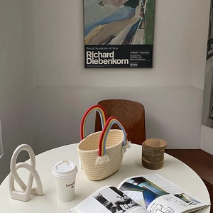 Detalle de bolso tejido crema con asas de arcoíris y flecos en un ambiente decorativo