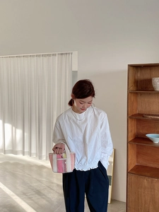 Gros plan d'un mini sac tissé rose et jaune avec poignée en tissu blanc et étiquette