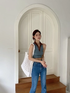 Detalle de un bolso grande de paja calado blanco con un top de punto a rayas de moda
