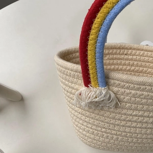 Detalle de asas de arcoíris y borlas de algodón en un bolso de crochet beige