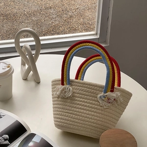 Primer plano del bolso tejido crema con asa trenzada de arcoíris y detalles de flecos