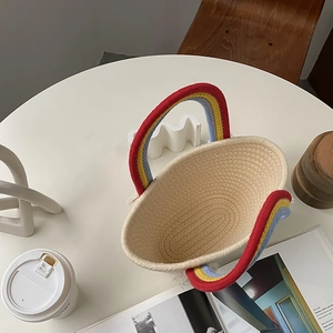 Detalle del bolso beige tejido a mano con borlas de arcoíris y asas de colores
