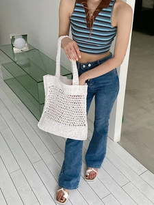 Detalle del bolso tote de ganchillo blanco con asas anchas tejidas y textura de malla calada