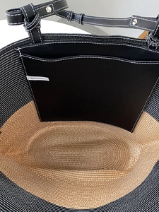 Dettaglio interno della borsa tote in paglia con pareti intrecciate e tasca in pelle