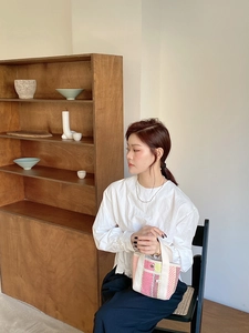 Gros plan du sac fourre-tout tissé à rayures roses et jaunes porté par un mannequin chic
