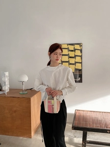 Détail d'un sac cabas tissé coloré tenu par un mannequin en chemise de coton blanc