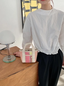 Détail du sac cabas tissé coloré avec poignée en tissu crème et fermeture à bouton