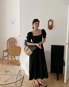 Dettaglio di una borsa tote in paglia intrecciata nera e naturale con abito midi nero