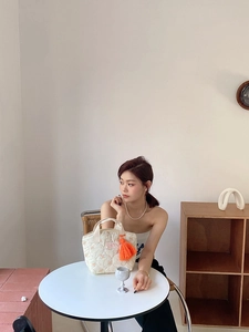 Détail du sac à déjeuner matelassé fleuri avec pompon orange sur table en bois