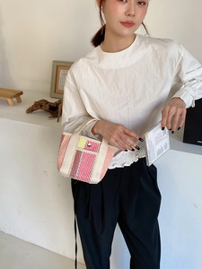 Détail du sac cabas tissé avec rayures roses et jaunes et fermeture par bouton en métal