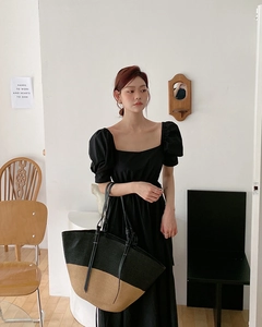 Dettaglio di una grande borsa tote in paglia con cuciture nere e stile estivo vacanziero